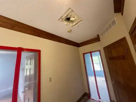 Room with a hole in the ceiling showing exposed insulation.