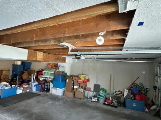 Damaged garage ceiling with exposed beams.