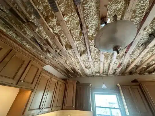 Exposed kitchen ceiling with water damage and foam insulation.